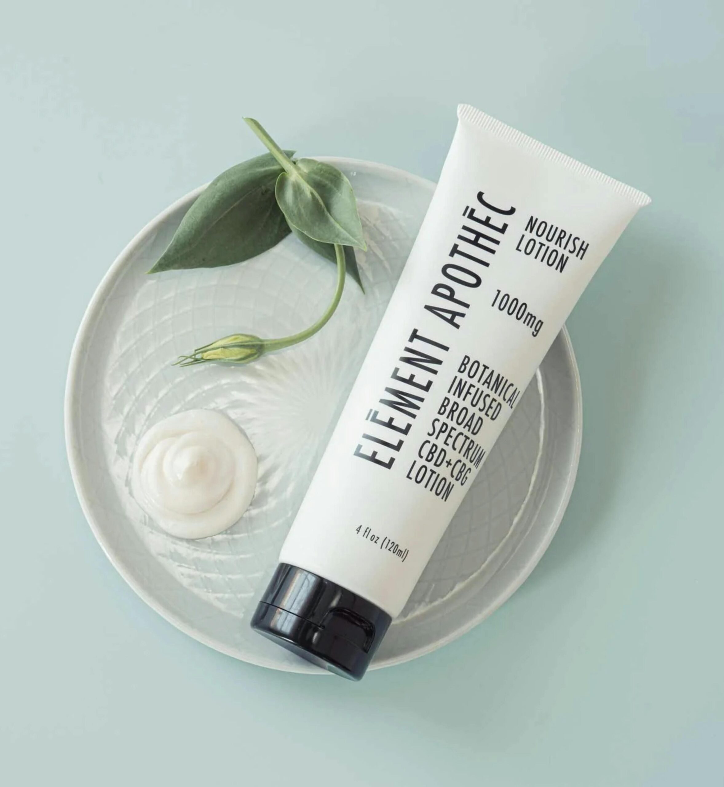 Element Apothec botanical lotion with CBD, surrounded by leaves and cream on a plate.