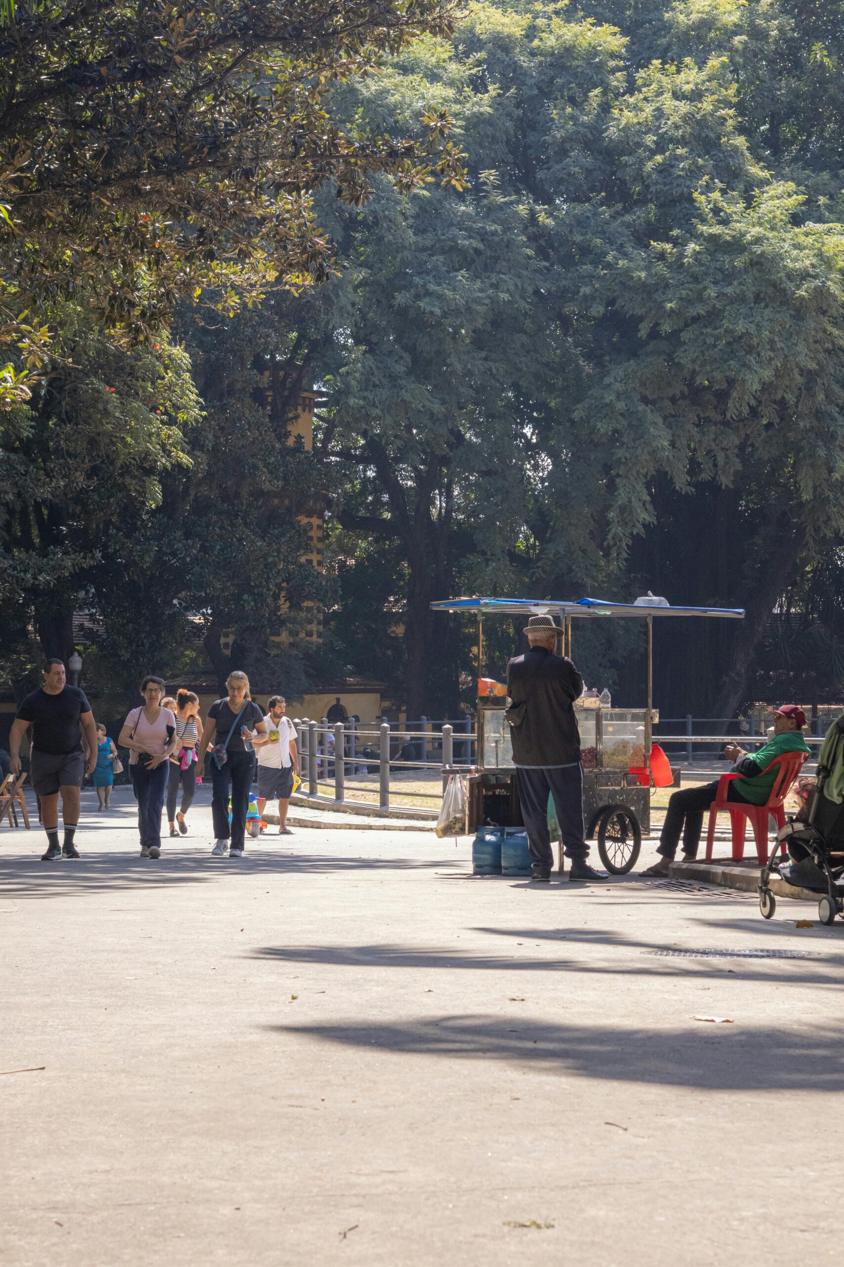 A vendor operates a cart in Ibirapuera Park, São Paulo, amid strolling visitors.