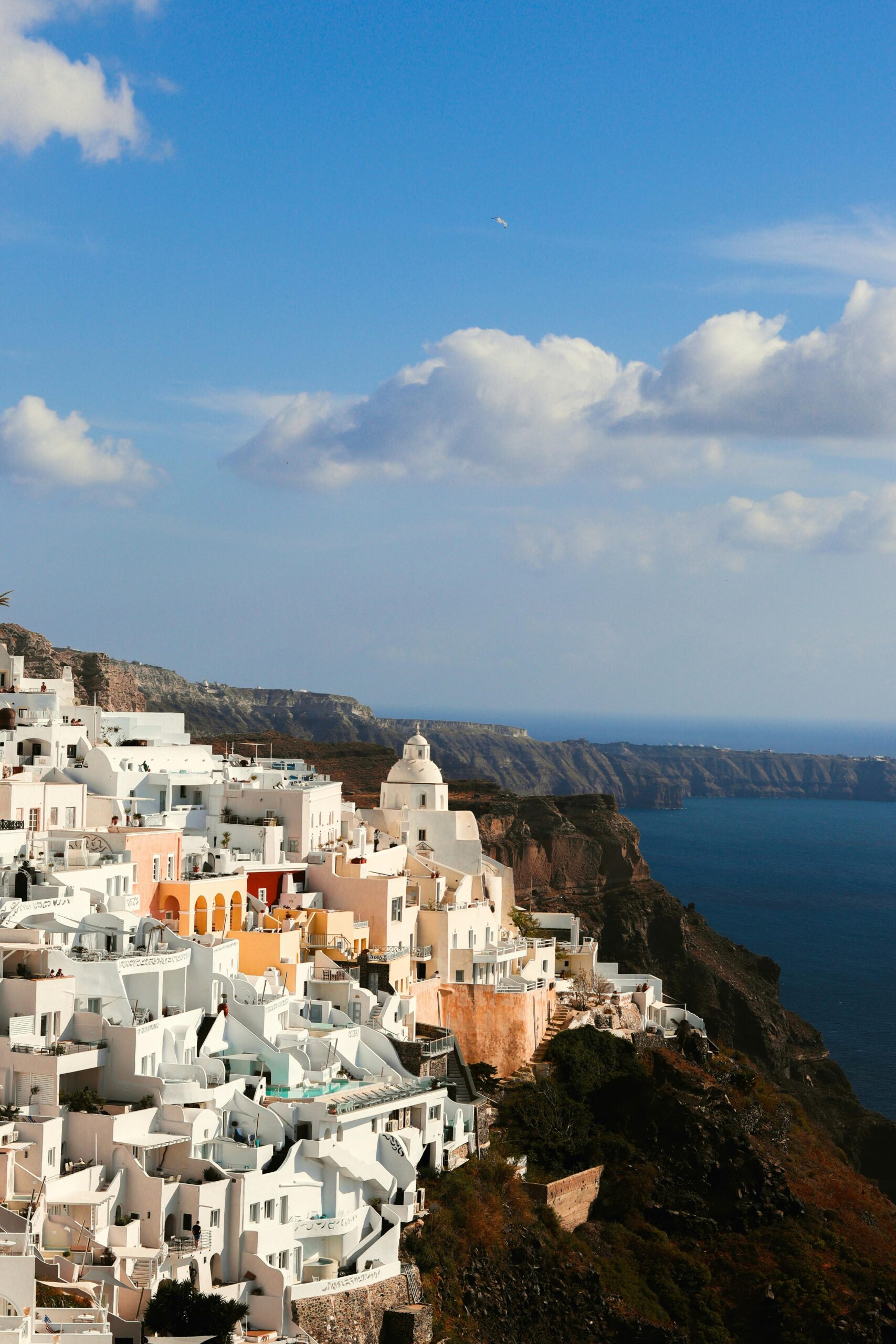 A scenic aerial view of Santorini's iconic whitewashed buildings perched on a cliff overlooking the Aegean Sea.