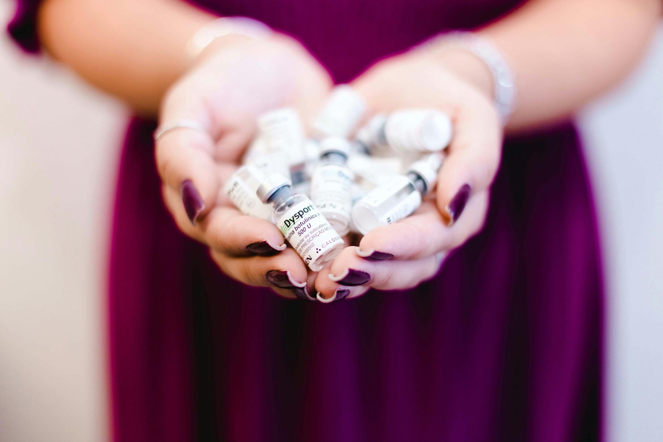 Close-up of a woman's hands holding multiple medical vials, emphasizing healthcare and cosmetic treatment.