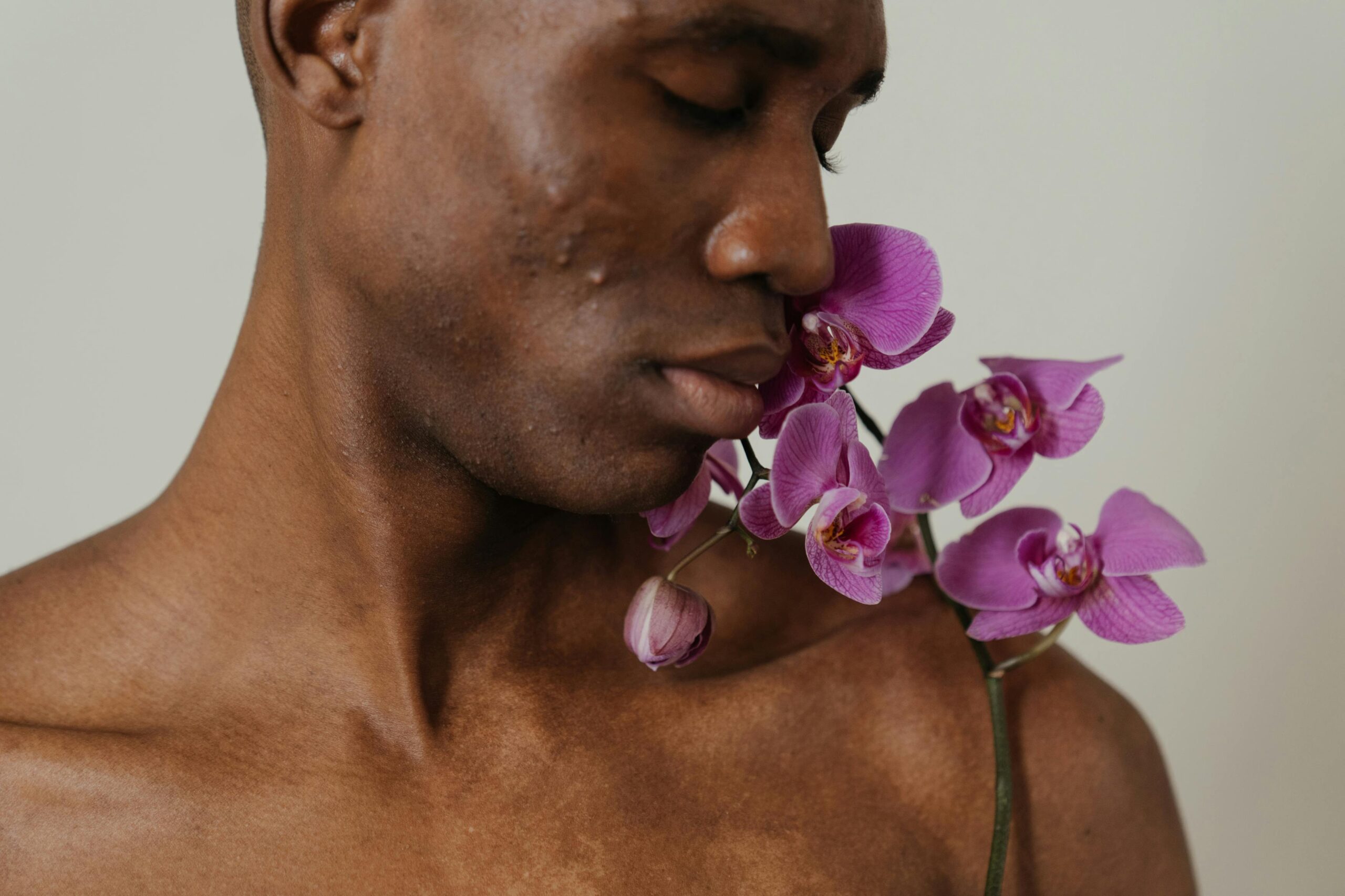 Close-up of a man with purple orchids, highlighting natural beauty and diversity.