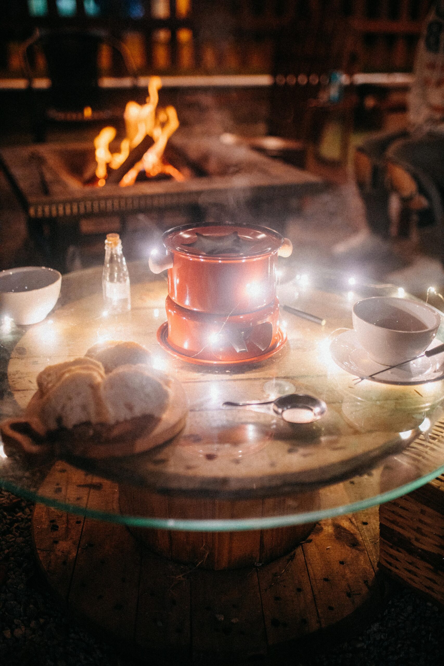 Warm and cozy outdoor evening scene with a fondue set, tea, and a fire pit atmosphere.