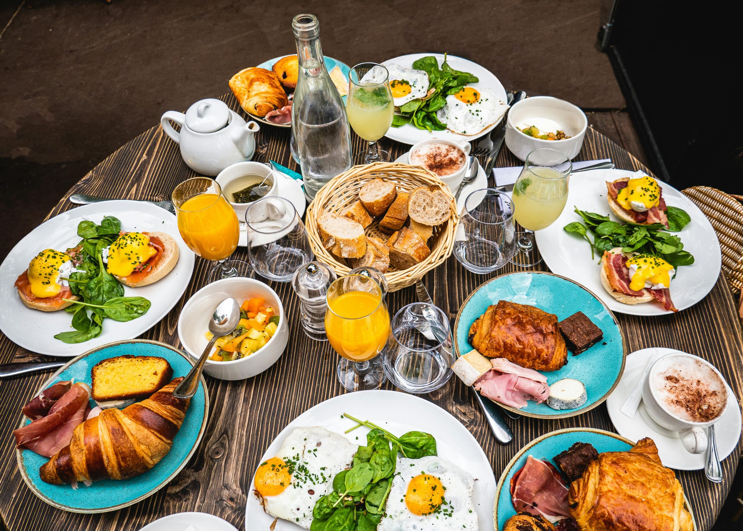 Savor the flavors of a classic Parisian brunch featuring croissants, eggs Benedict, and fresh juice on a wooden table.
