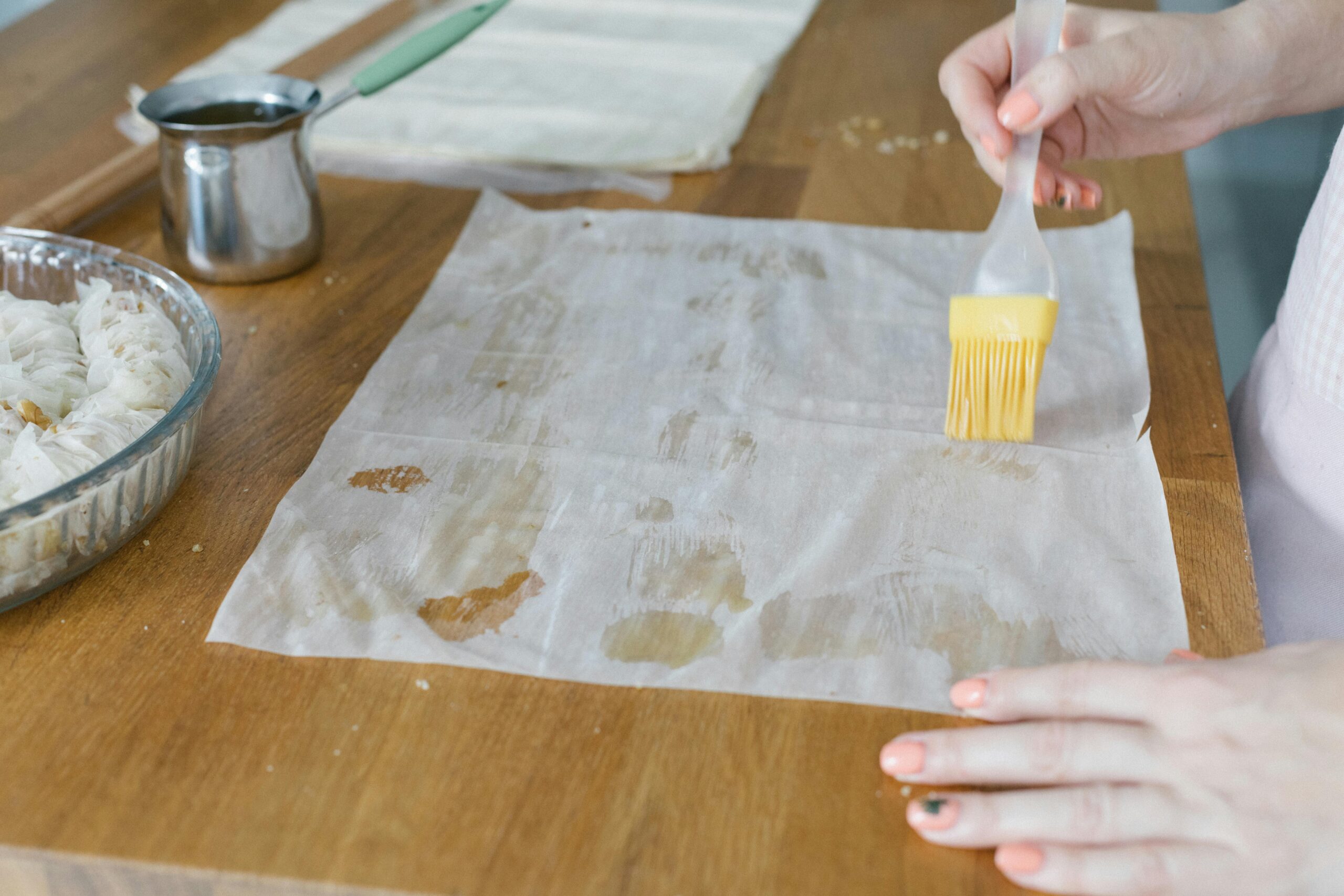 A close-up of hands making baklava with phyllo dough, showcasing traditional Turkish cuisine.