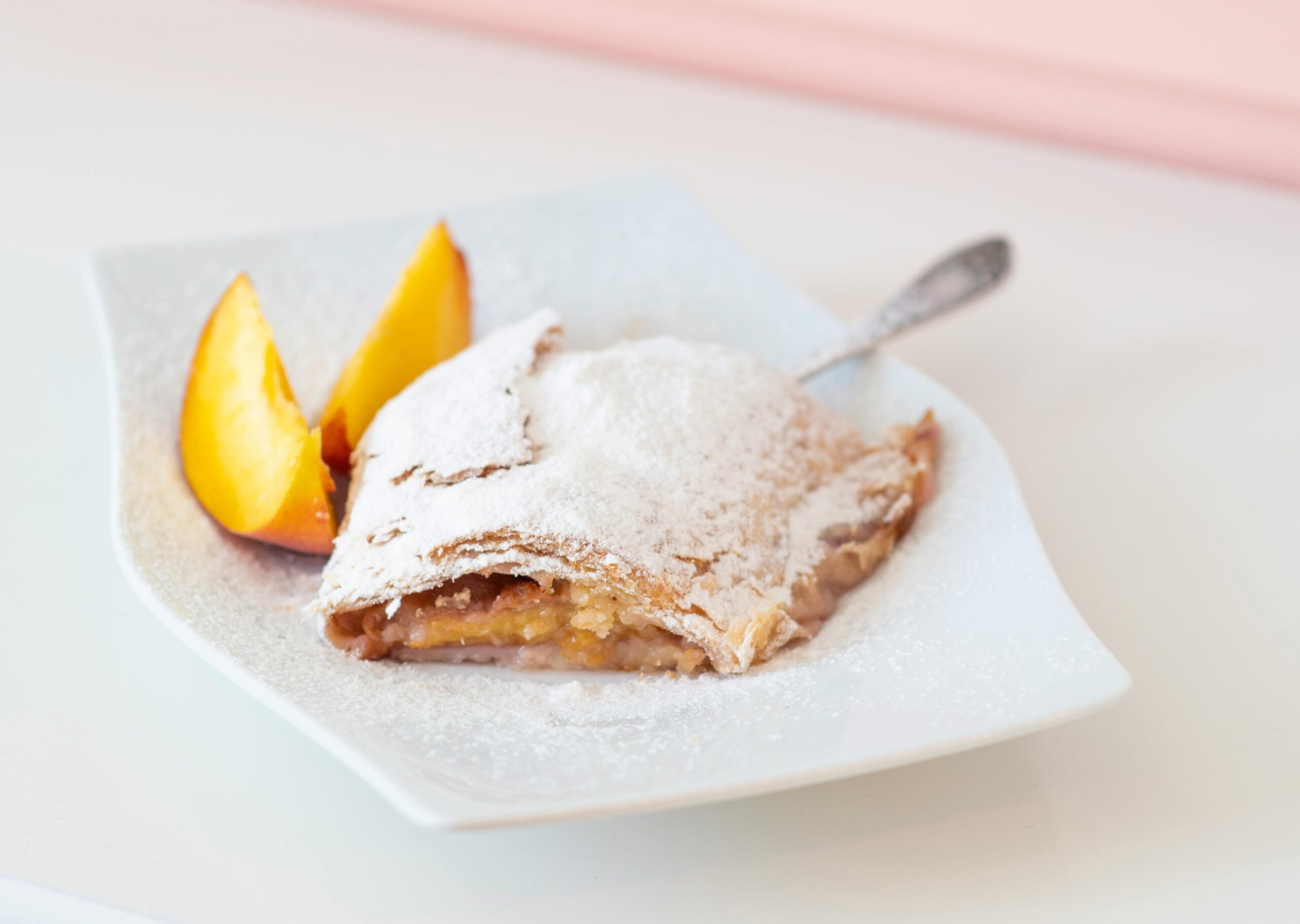Mouthwatering peach strudel topped with powdered sugar, perfect for dessert lovers.