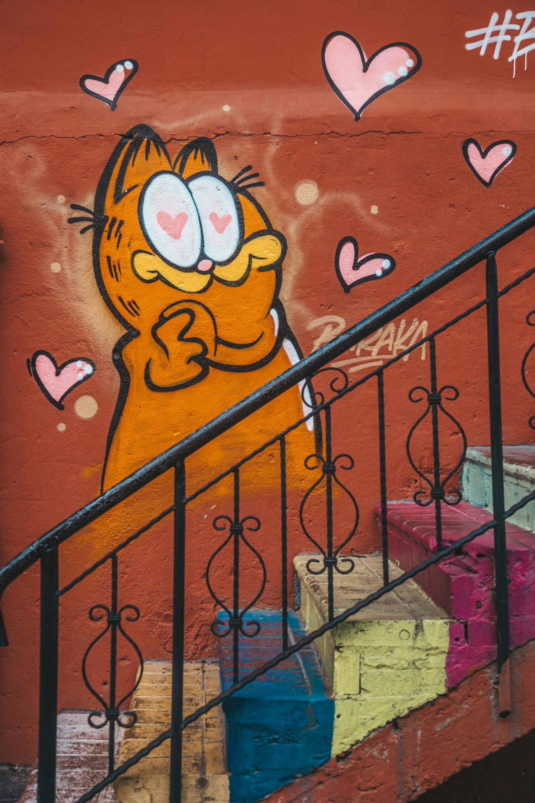 Vibrant street art featuring Garfield and heart motifs on a colorful staircase.