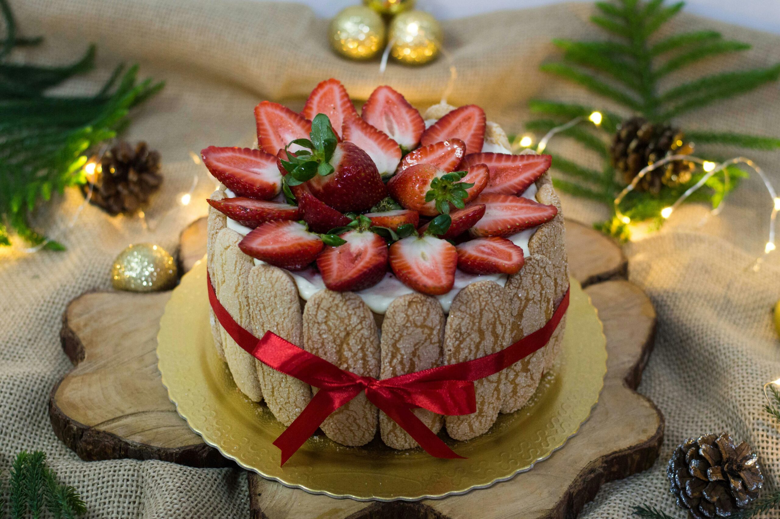 Delicious charlotte cake adorned with fresh strawberries and festive decor, perfect for Christmas celebrations.