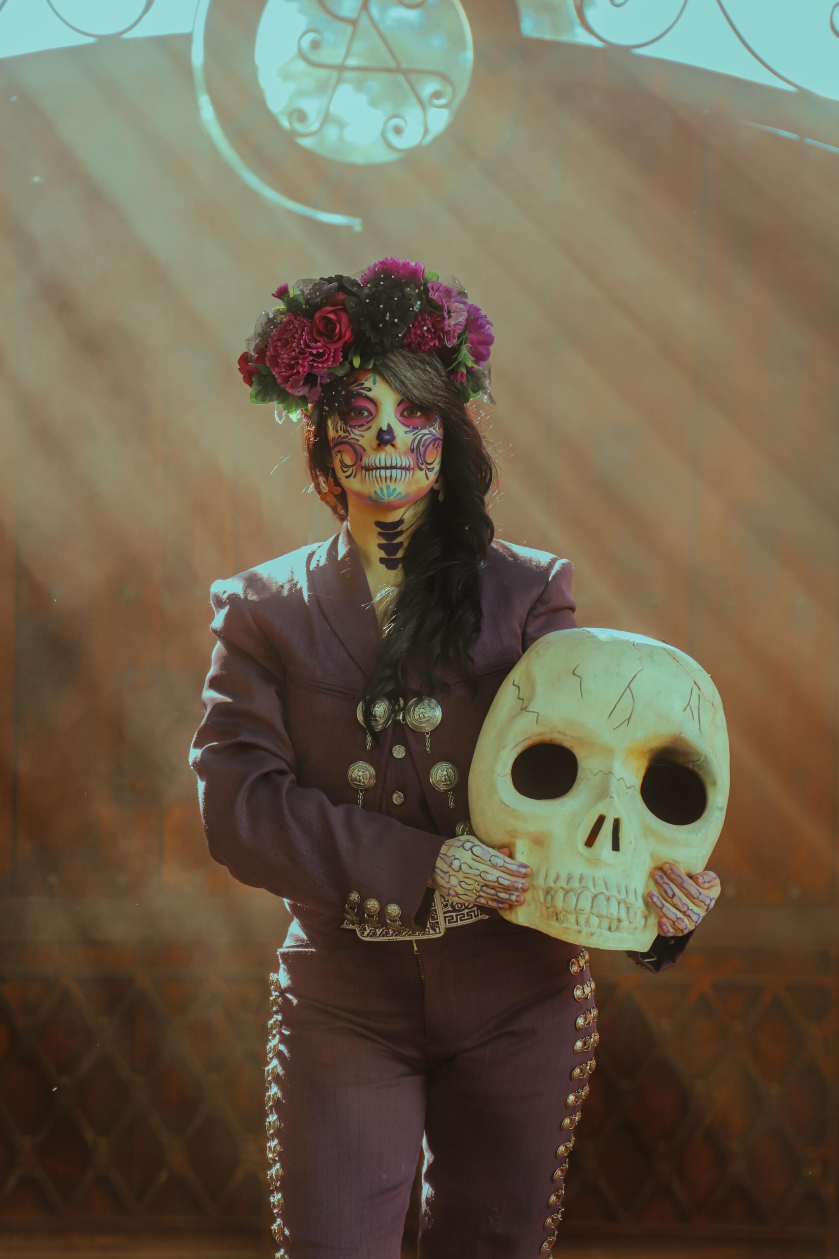 Vibrant Día de Muertos image of a woman with decorative face paint, holding a skull.