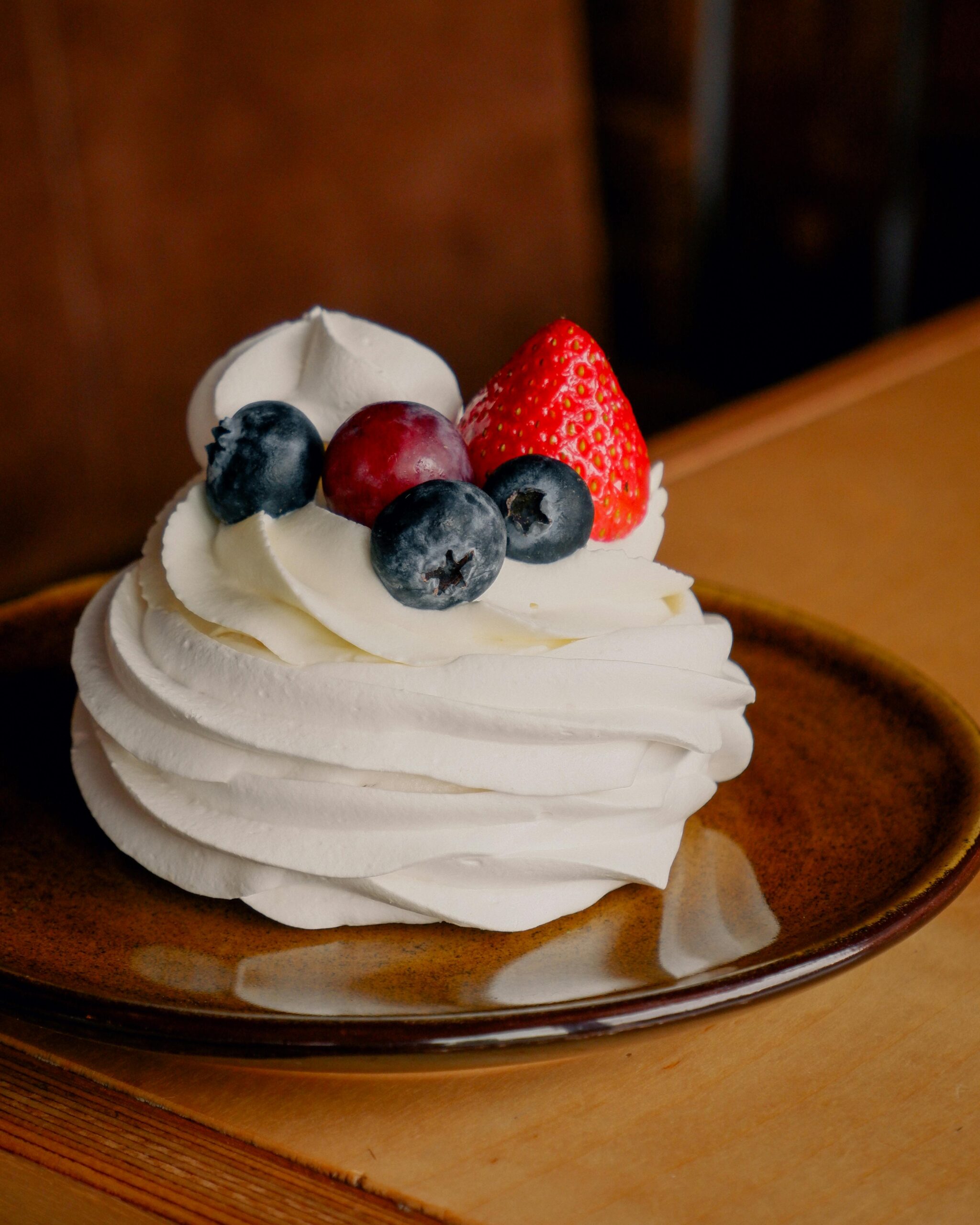 A close-up of a creamy pavlova topped with fresh berries, perfect for dessert ideas.
