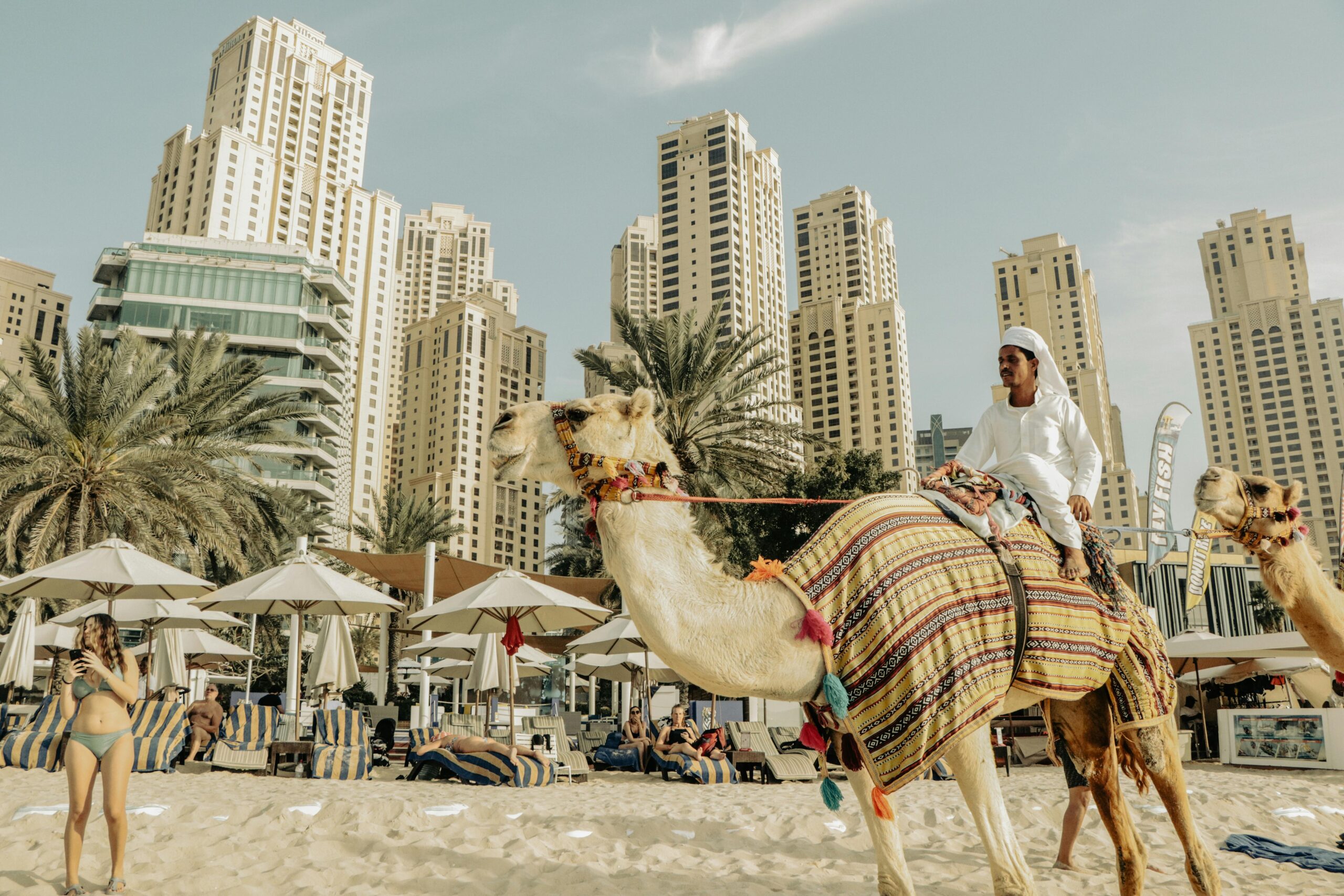 Camel rides on Dubai Marina beach with iconic skyscrapers in the background.