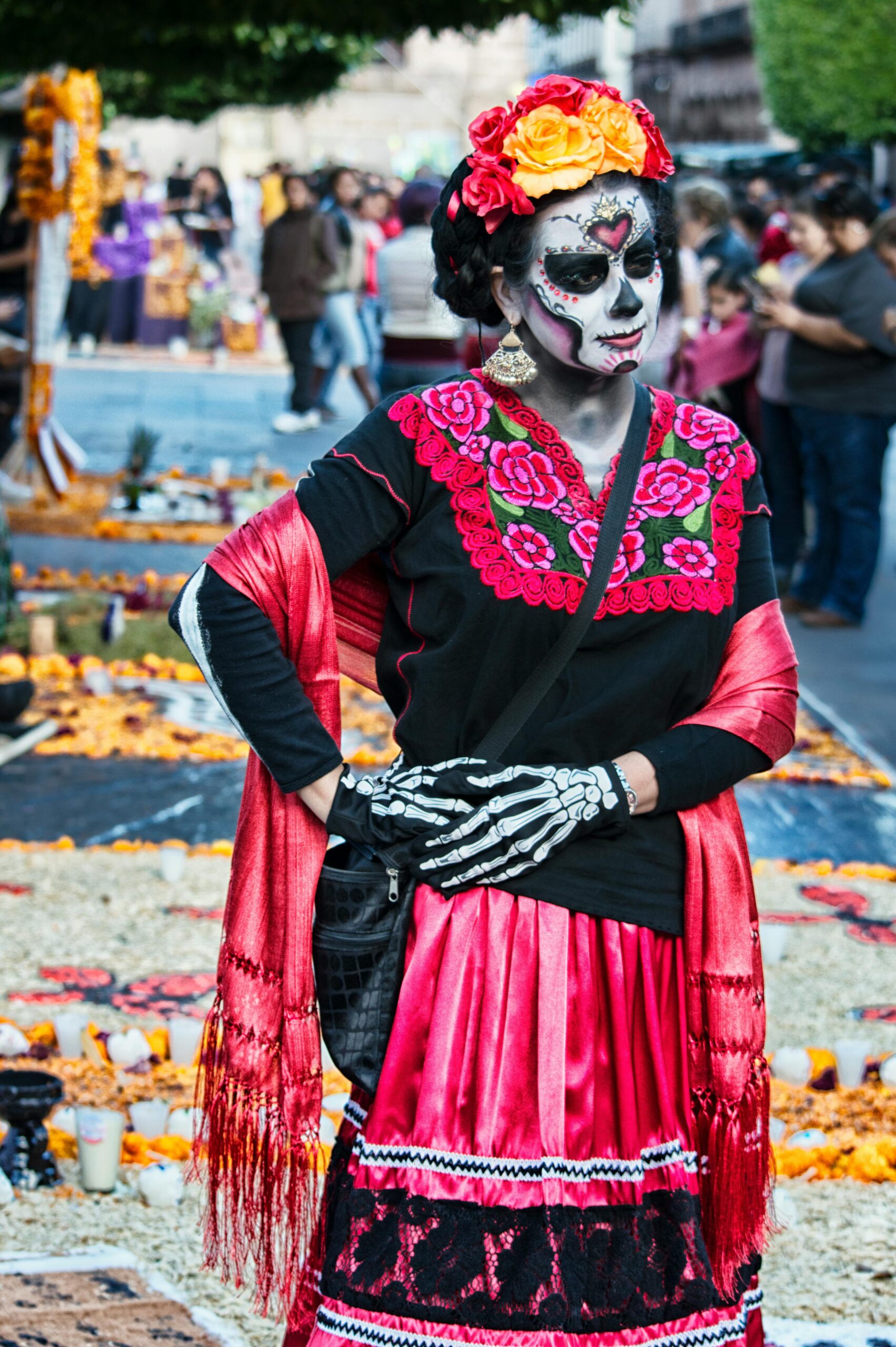 Woman in traditional Day of the Dead costume and face paint at a festive parade in Mexico City.