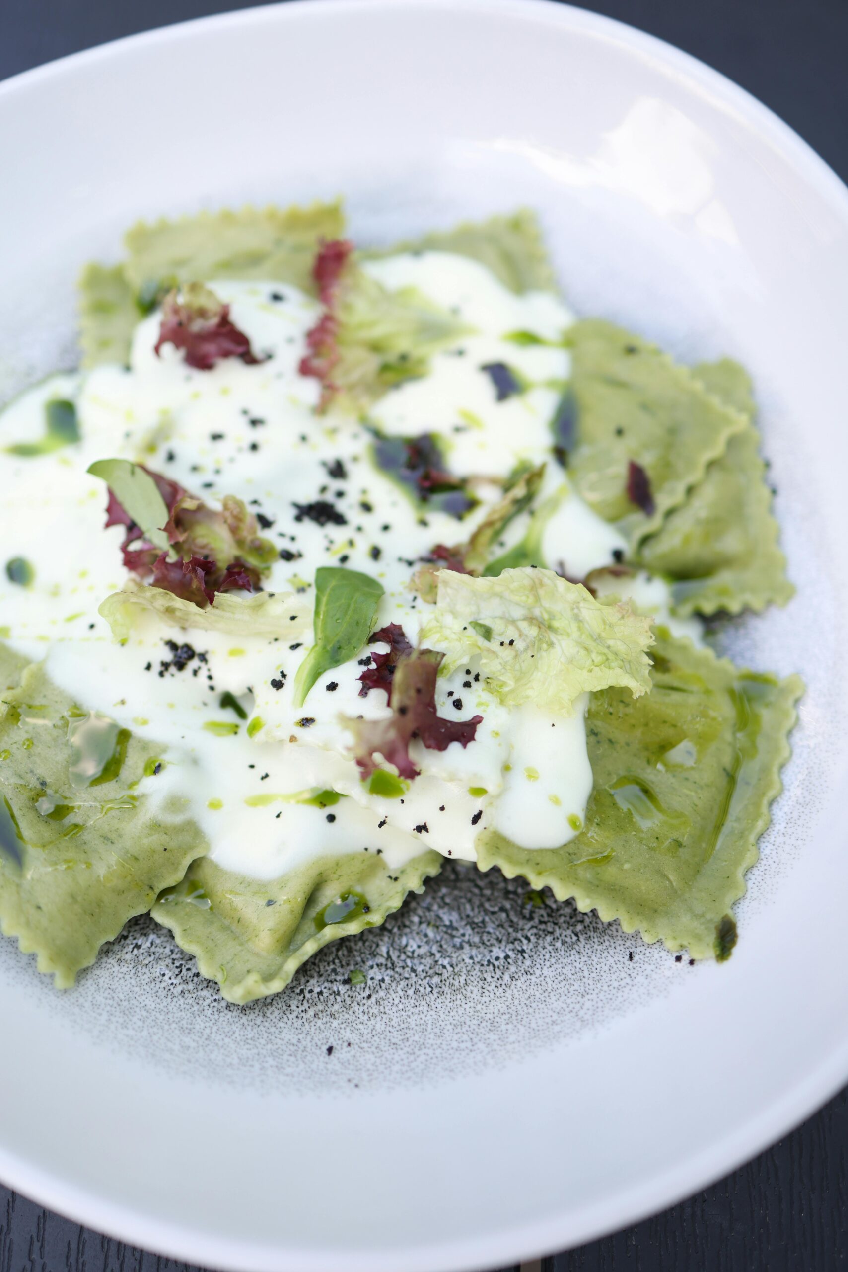 Delicious green ravioli topped with creamy sauce and herbs. Perfect gourmet meal.