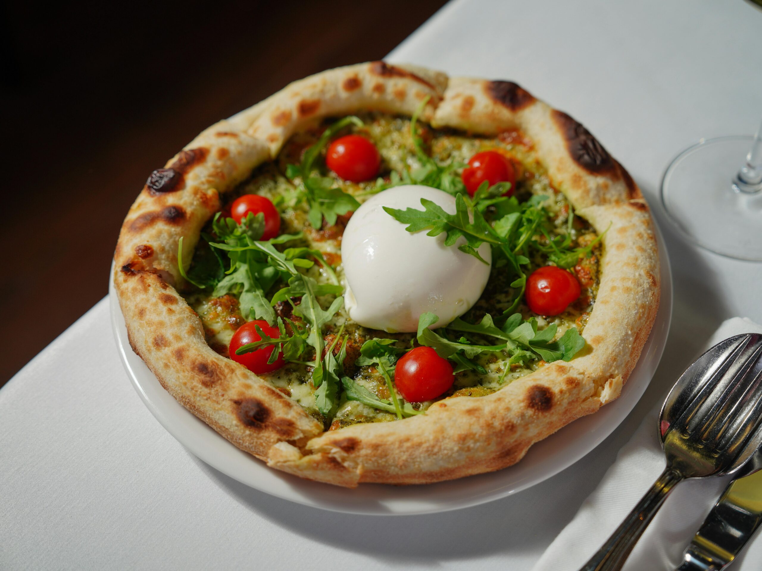 Close-up of a delicious pizza topped with creamy burrata, cherry tomatoes, and fresh arugula.