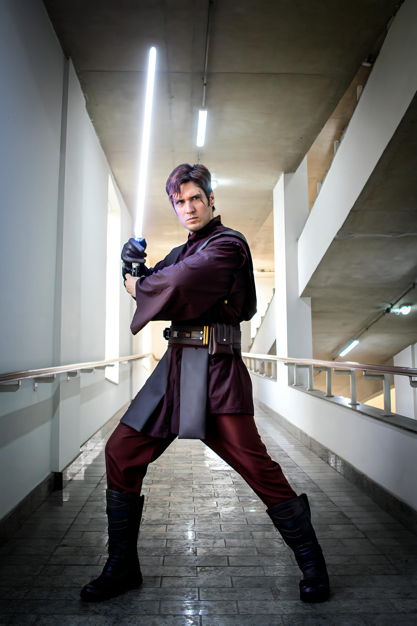 Man in Star Wars cosplay holding a lightsaber, indoors, São Paulo, Brazil.
